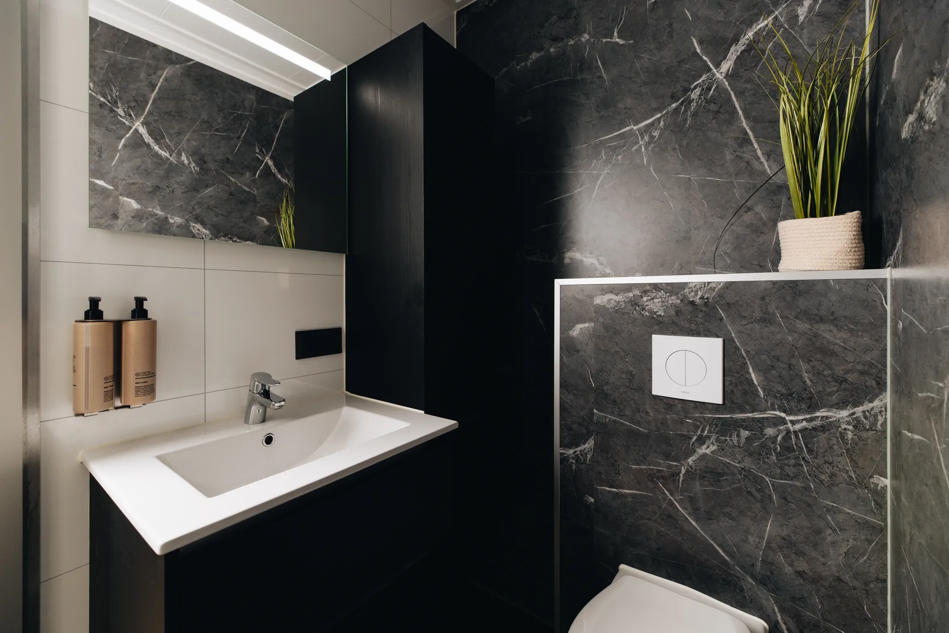 Detail van de moderne wastafel en verlichte spiegel in de luxe marmeren badkamer van Resort Land & Zee.